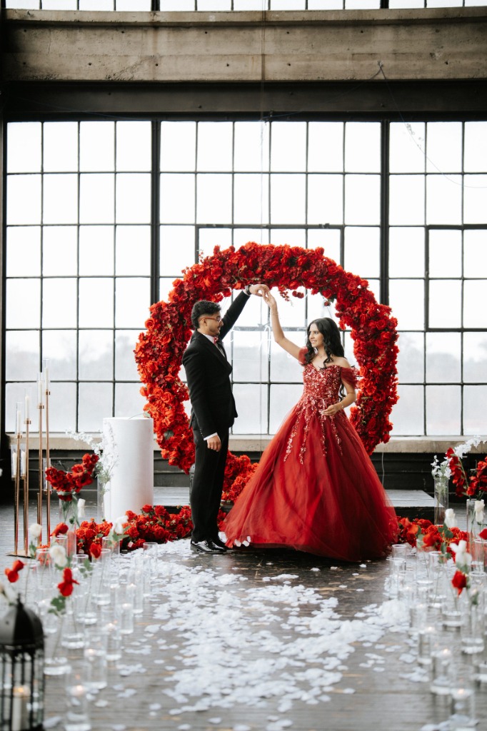 Sonali and Gagan Dancing in Front of Red Floral Arch
